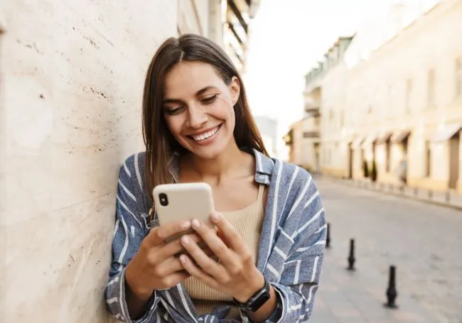 Una chica sonríe mientras utiliza su teléfono durante un viaje al extranjero.