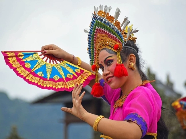 Una mujer en traje tradicional sostiene un abanico, ilustrando la cultura y la elegancia de su herencia.