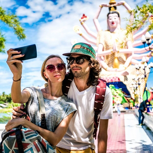 Una pareja se toma un selfie delante de una estatua, captando un momento feliz y memorable juntos.